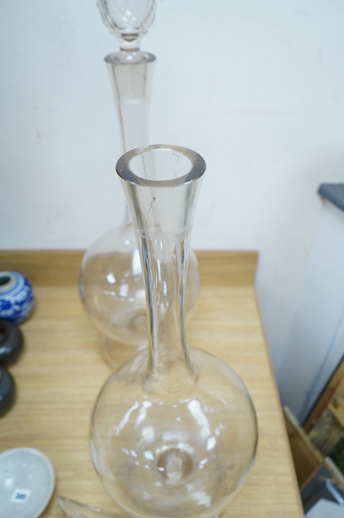 A pair of large clear glass chemist window display bottles and stoppers, one with chip, 90cm high
